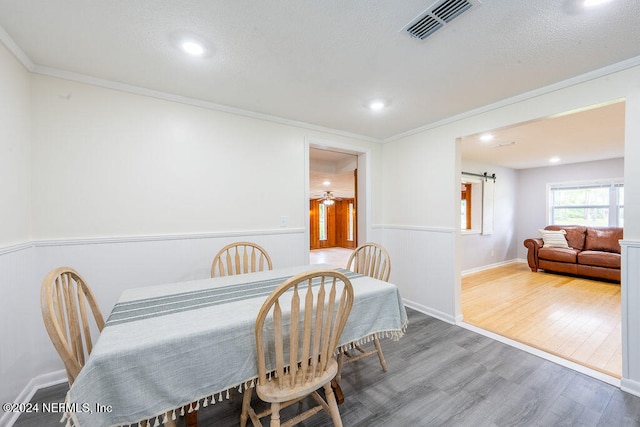 dining room with ceiling fan, ornamental molding, a textured ceiling, hardwood / wood-style flooring, and a barn door