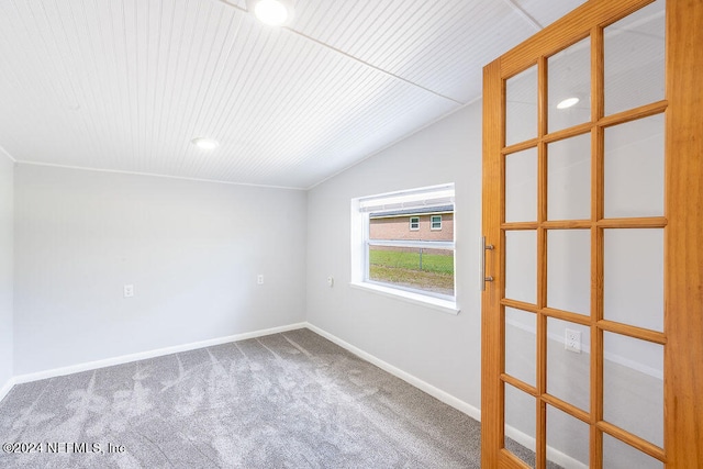 carpeted empty room with lofted ceiling