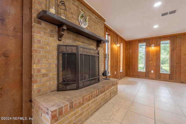 unfurnished living room featuring light tile patterned flooring, a brick fireplace, and wood walls