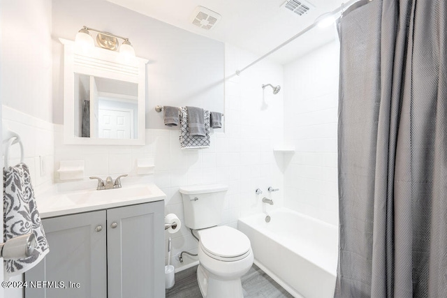 full bathroom with shower / tub combo with curtain, tile walls, vanity, and toilet