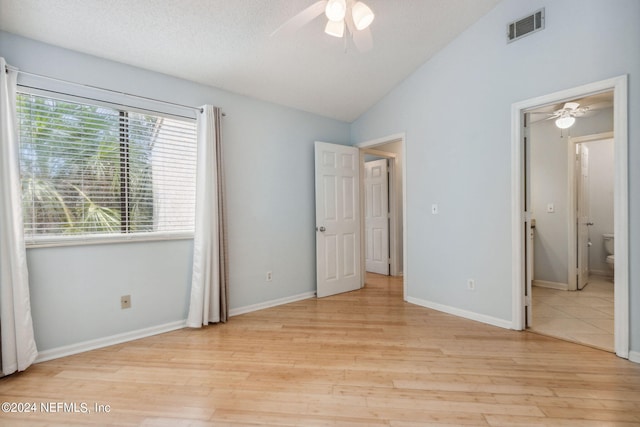 unfurnished bedroom with ceiling fan, light hardwood / wood-style floors, connected bathroom, a textured ceiling, and vaulted ceiling