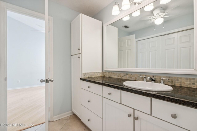 bathroom featuring ceiling fan, vanity, a textured ceiling, backsplash, and tile patterned floors