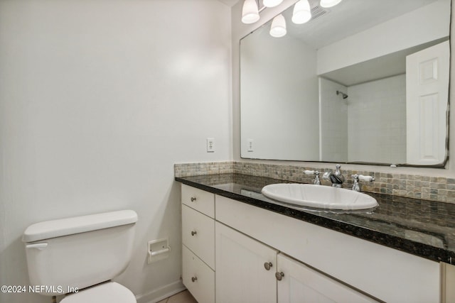 bathroom with a tile shower, vanity, toilet, and tasteful backsplash