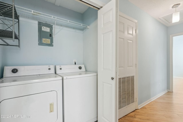 clothes washing area featuring electric panel, light hardwood / wood-style flooring, and independent washer and dryer