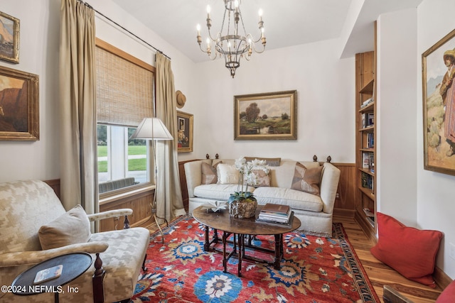 living area with hardwood / wood-style flooring, wood walls, and a notable chandelier