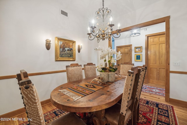 dining area with wood-type flooring and an inviting chandelier