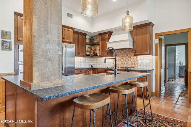 kitchen with a high ceiling, decorative backsplash, a breakfast bar area, and high end refrigerator