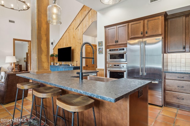 kitchen with a kitchen island with sink, appliances with stainless steel finishes, sink, and a high ceiling