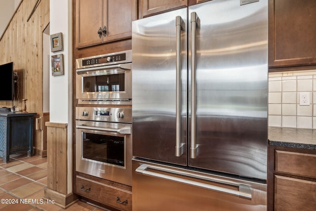 kitchen with appliances with stainless steel finishes, backsplash, and light tile patterned floors