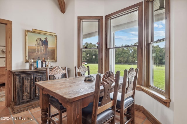 dining area featuring beamed ceiling, light tile patterned floors, and a wealth of natural light