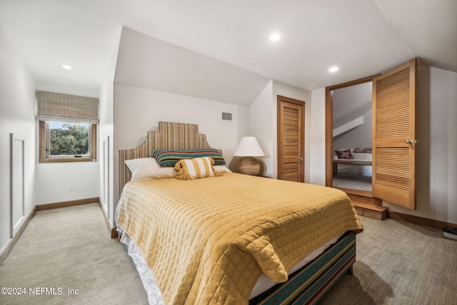 bedroom featuring a closet, vaulted ceiling, and light carpet