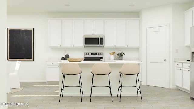 kitchen with stainless steel electric range oven, a center island with sink, white cabinets, and light hardwood / wood-style floors