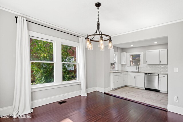 kitchen with pendant lighting, white cabinets, an inviting chandelier, hardwood / wood-style floors, and stainless steel dishwasher