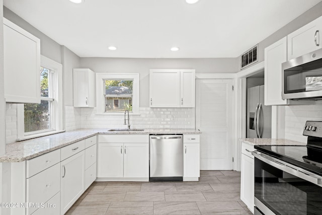 kitchen with light stone countertops, sink, stainless steel appliances, and white cabinets