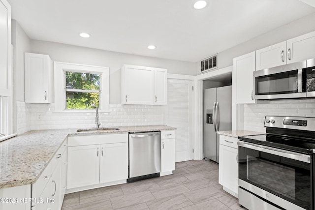 kitchen featuring light stone countertops, white cabinetry, appliances with stainless steel finishes, and sink