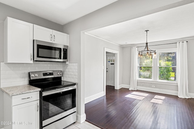 kitchen featuring hardwood / wood-style flooring, white cabinetry, an inviting chandelier, decorative backsplash, and appliances with stainless steel finishes