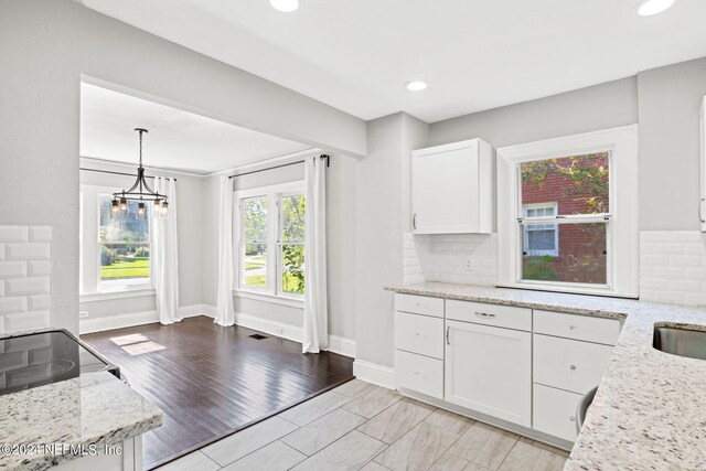 kitchen with light stone counters, decorative light fixtures, light hardwood / wood-style floors, and white cabinetry