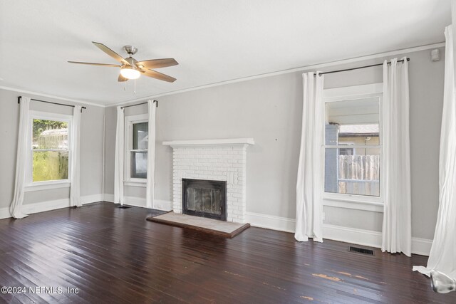 unfurnished living room featuring ceiling fan, dark hardwood / wood-style floors, a fireplace, and crown molding