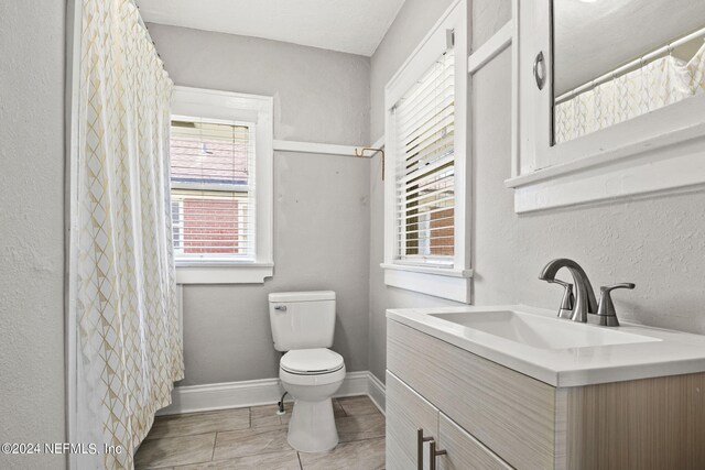 bathroom with tile patterned flooring, a shower with curtain, vanity, and toilet