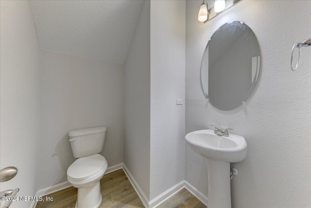 bathroom featuring a textured ceiling, lofted ceiling, toilet, and hardwood / wood-style flooring