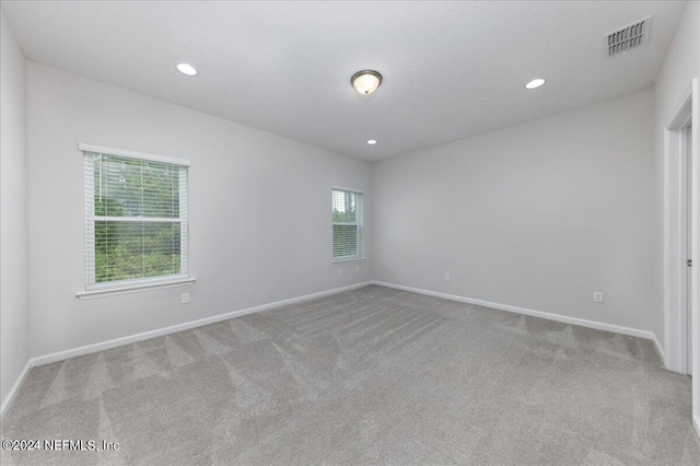 carpeted empty room featuring a textured ceiling