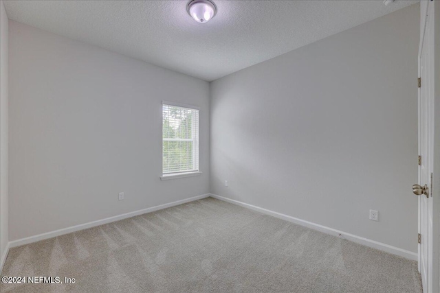 unfurnished room with light carpet and a textured ceiling