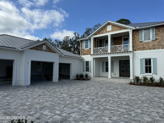 view of front facade featuring a garage, metal roof, a standing seam roof, decorative driveway, and stucco siding