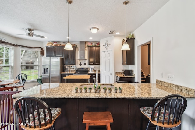 kitchen featuring kitchen peninsula, stainless steel fridge, hanging light fixtures, and a textured ceiling