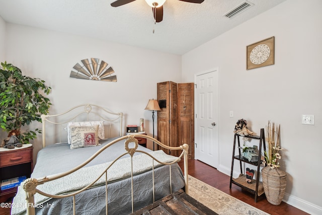 bedroom featuring ceiling fan, dark hardwood / wood-style flooring, and a textured ceiling