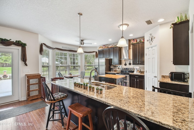 kitchen featuring dark brown cabinets, stainless steel appliances, dark wood-type flooring, sink, and hanging light fixtures