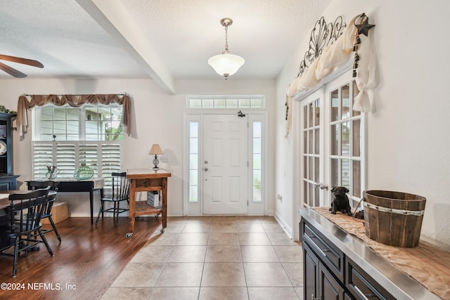 foyer featuring ceiling fan, beam ceiling, a textured ceiling, and light hardwood / wood-style flooring