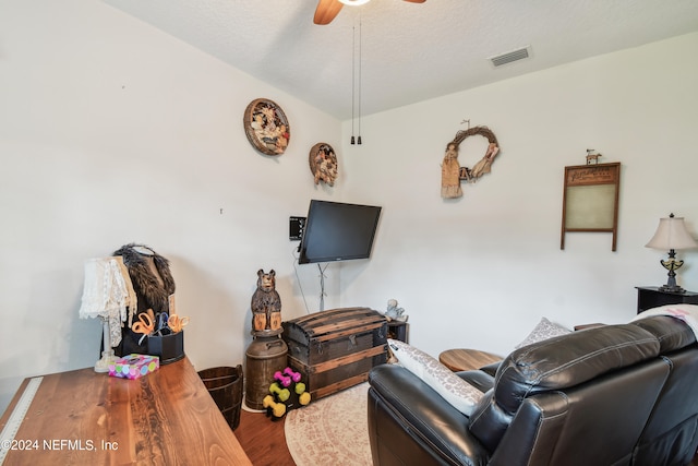 living room featuring ceiling fan, wood-type flooring, and a textured ceiling