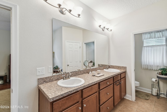 bathroom with tile patterned flooring, vanity, a textured ceiling, and toilet