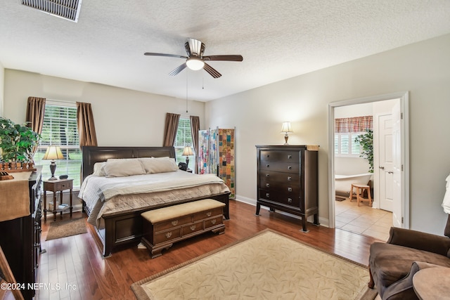 bedroom with hardwood / wood-style floors, ceiling fan, a textured ceiling, and multiple windows