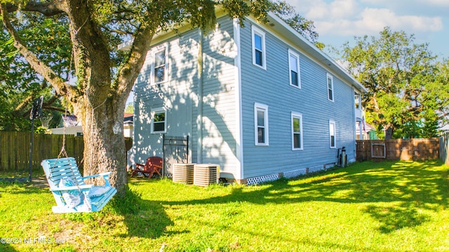 rear view of property featuring central AC unit and a yard