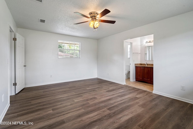 unfurnished bedroom featuring a sink, dark wood-style flooring, a textured ceiling, and visible vents