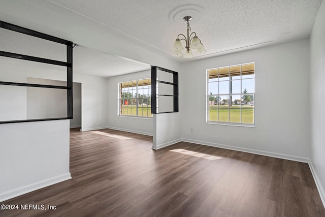 unfurnished room with a notable chandelier, a textured ceiling, and dark hardwood / wood-style flooring