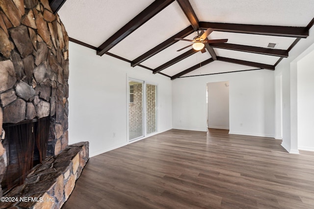 unfurnished living room with a ceiling fan, vaulted ceiling with beams, wood finished floors, a stone fireplace, and baseboards