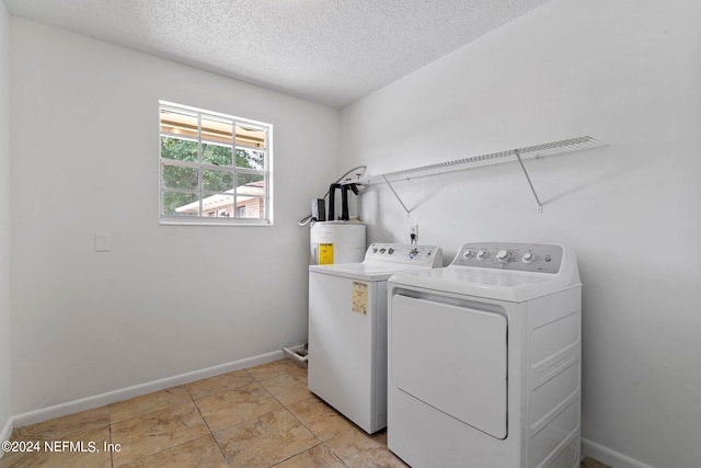 laundry area with a textured ceiling, washing machine and dryer, and electric water heater