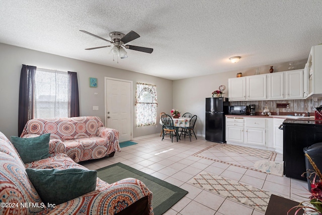 living room featuring a textured ceiling, light tile patterned floors, and ceiling fan