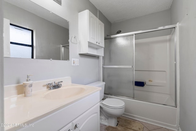 bathroom with tile patterned floors, toilet, vanity, a textured ceiling, and shower / bath combination with glass door