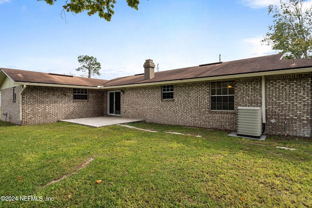 back of property with a lawn, a patio area, central AC, and brick siding
