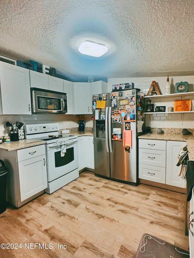 kitchen featuring white cabinets, a textured ceiling, stainless steel appliances, and light hardwood / wood-style flooring