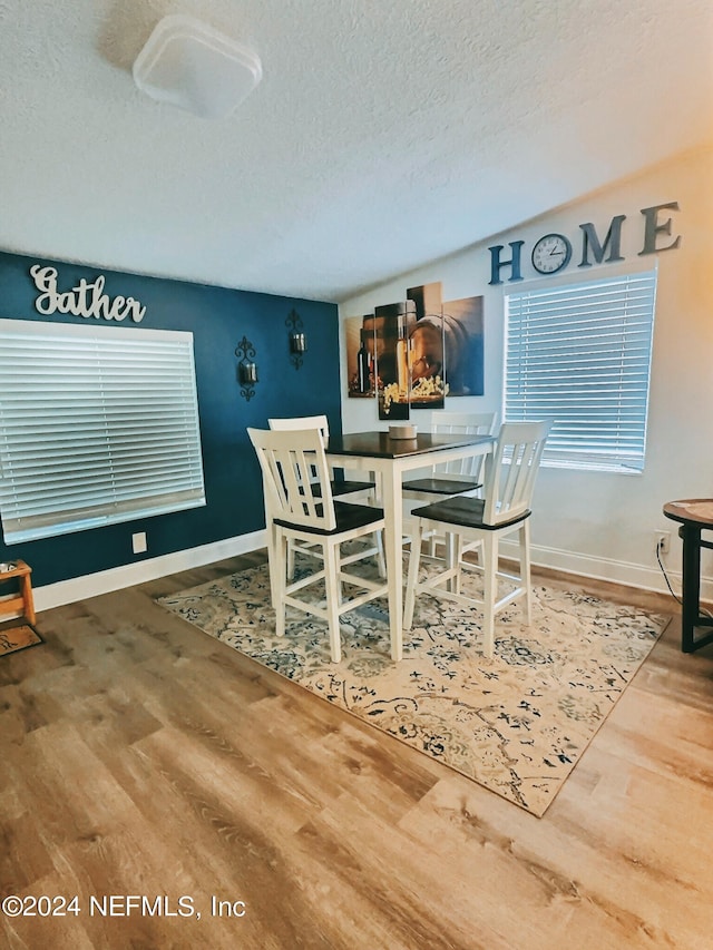 dining space featuring wood-type flooring and a textured ceiling