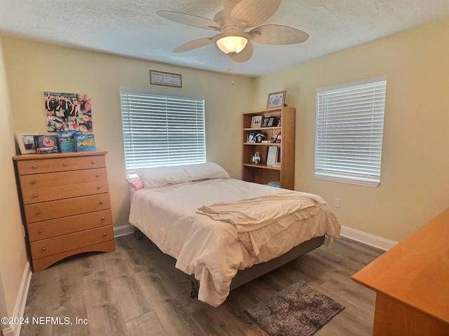 bedroom with a textured ceiling, ceiling fan, and hardwood / wood-style flooring