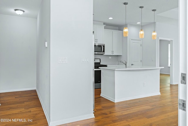 kitchen with appliances with stainless steel finishes, white cabinetry, dark hardwood / wood-style flooring, decorative light fixtures, and a center island with sink