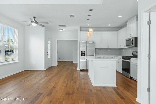 kitchen with pendant lighting, dark hardwood / wood-style floors, a kitchen island with sink, white cabinets, and stainless steel appliances