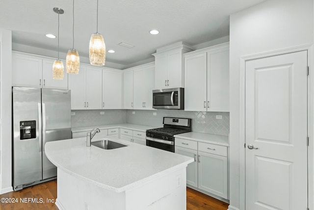 kitchen featuring hanging light fixtures, sink, a center island with sink, white cabinetry, and stainless steel appliances