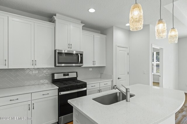 kitchen with white cabinets, sink, a center island with sink, appliances with stainless steel finishes, and dark hardwood / wood-style flooring