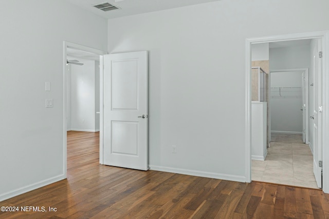 unfurnished bedroom with a spacious closet, a closet, and dark hardwood / wood-style flooring